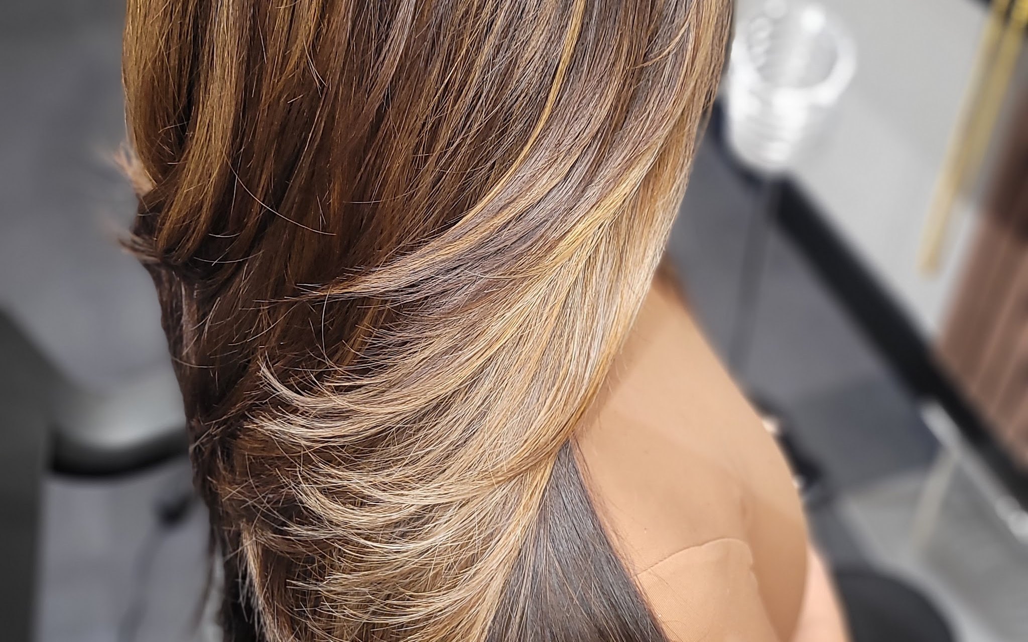 Lange bruine lengtes met een warme balayage, van achteren gezien in de salon