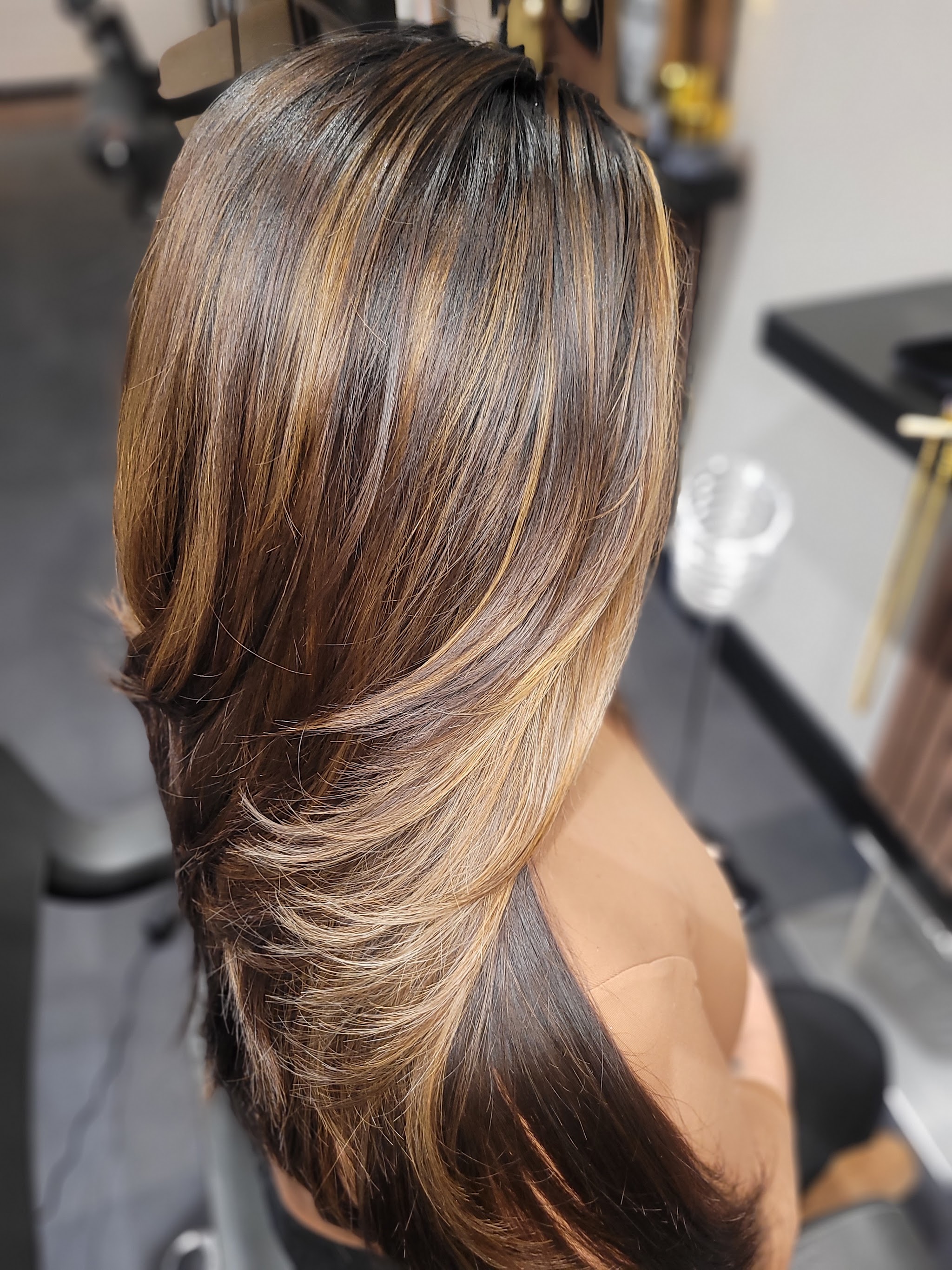 Lange bruine lengtes met een warme balayage, van achteren gezien in de salon