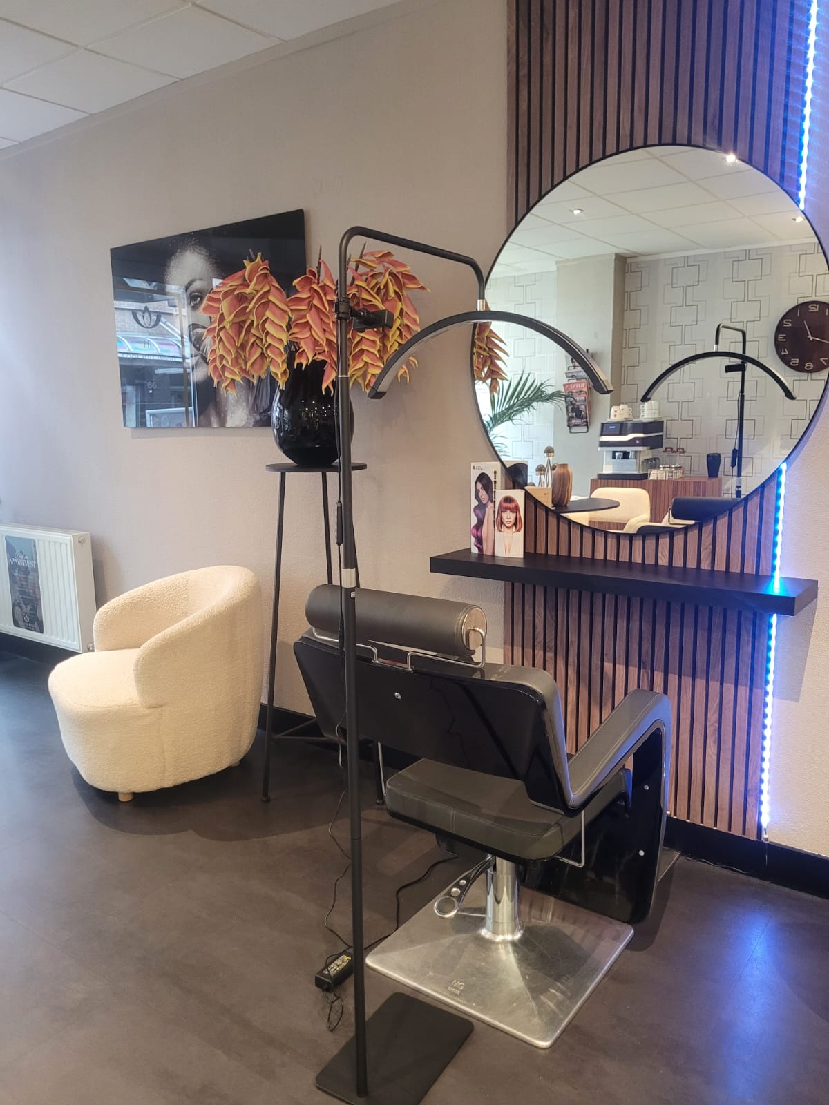 Een werkplek in de salon met ronde spiegel, houten lamellen en een crèmekleurige fauteuil