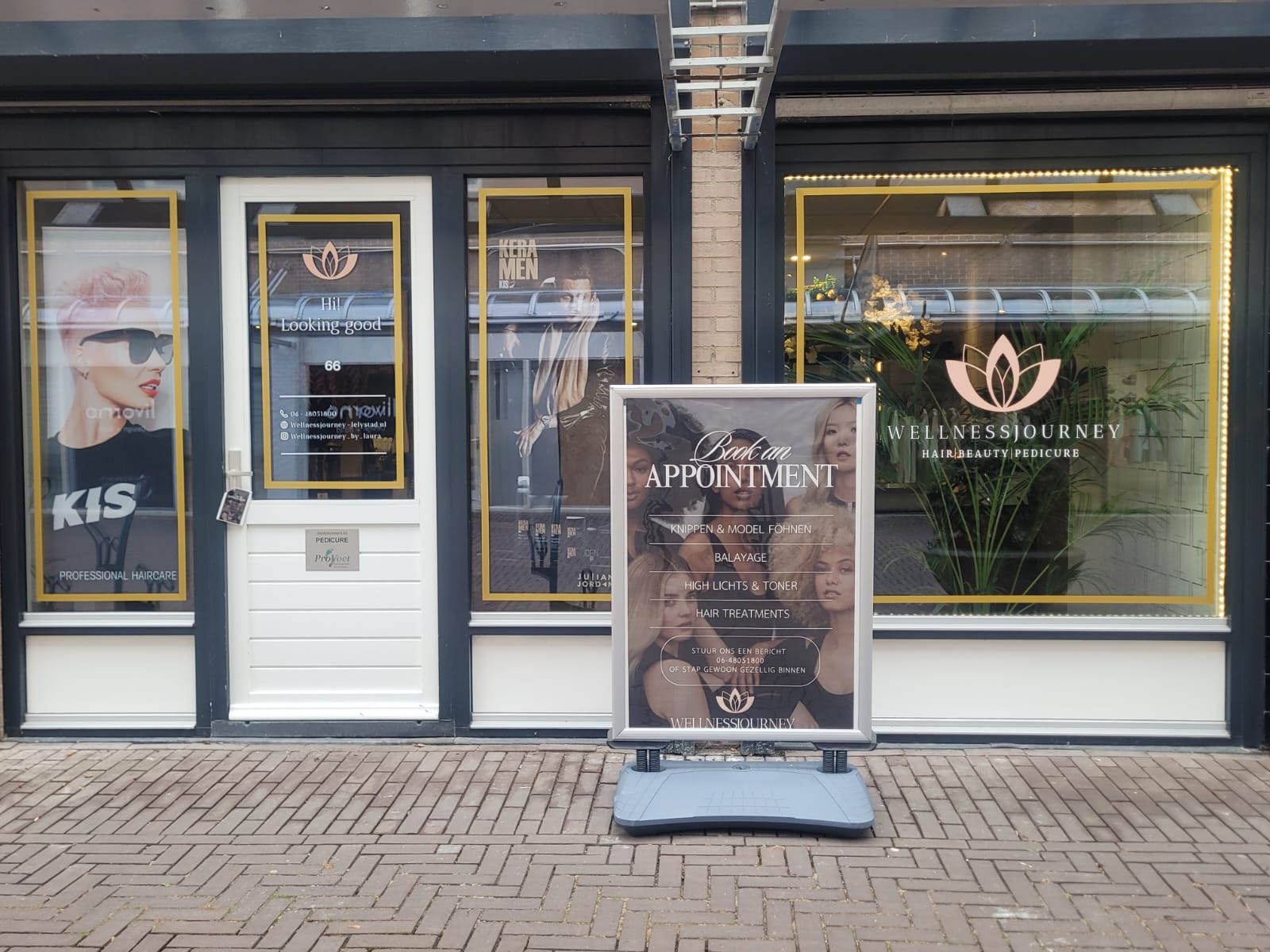 De gevel van Wellnessjourney aan de Stadhuisstraat met de lotus op het raam en het bord op de stoep