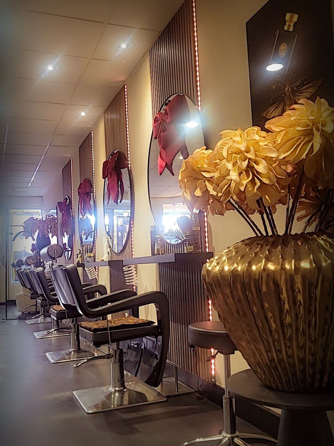 De rij stoelen in de salon met ronde spiegels en een gouden vaas met gele bloemen